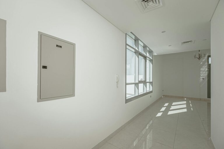 A clean, minimalistic empty corridor with natural light streaming through large windows.