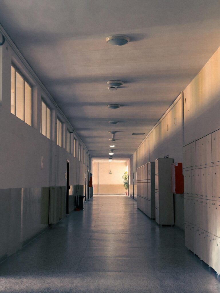Deserted corridor in a school, featuring rows of lockers and warm ambient light.