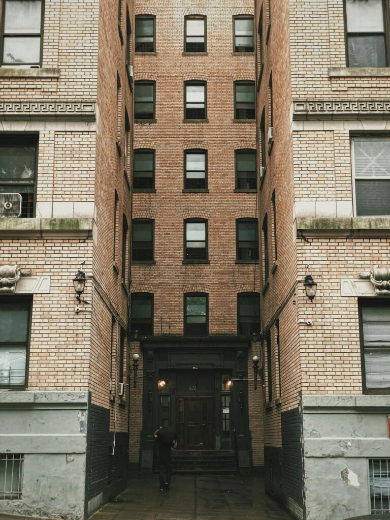 Vertical view of a narrow urban alley between brick apartment buildings with a central entrance doorway.