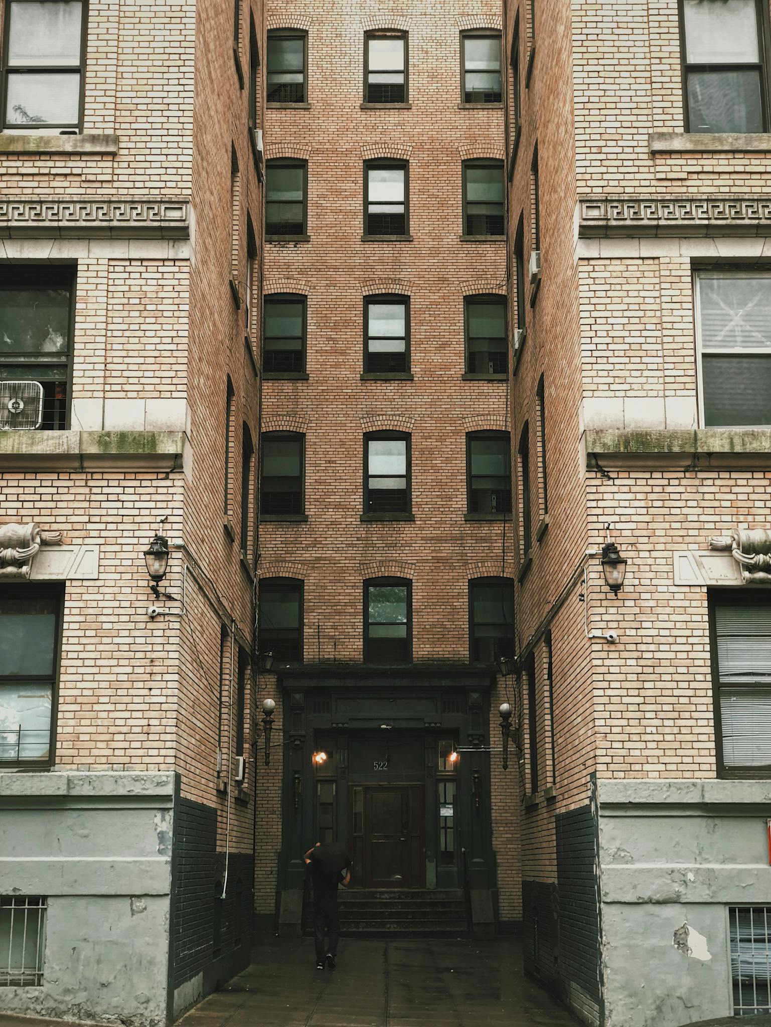 Vertical view of a narrow urban alley between brick apartment buildings with a central entrance doorway.