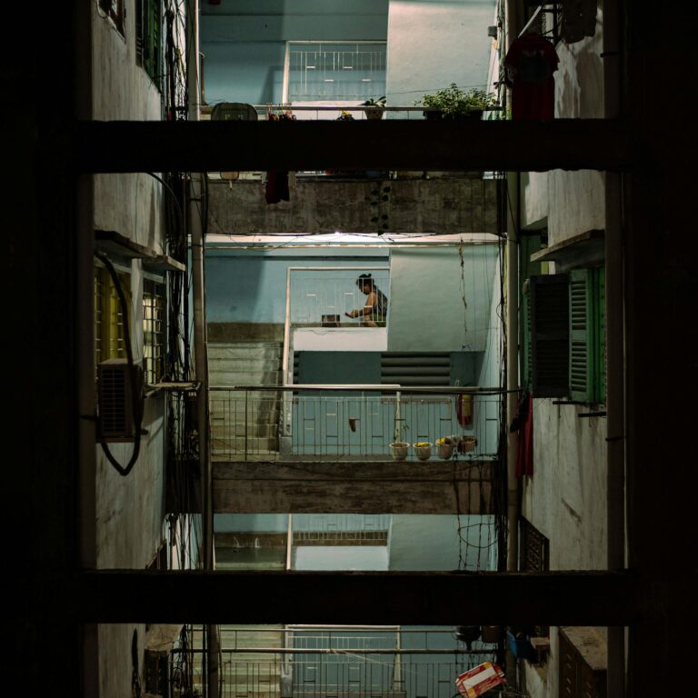 View of a multi-story urban building interior, showcasing railings and balconies at night.