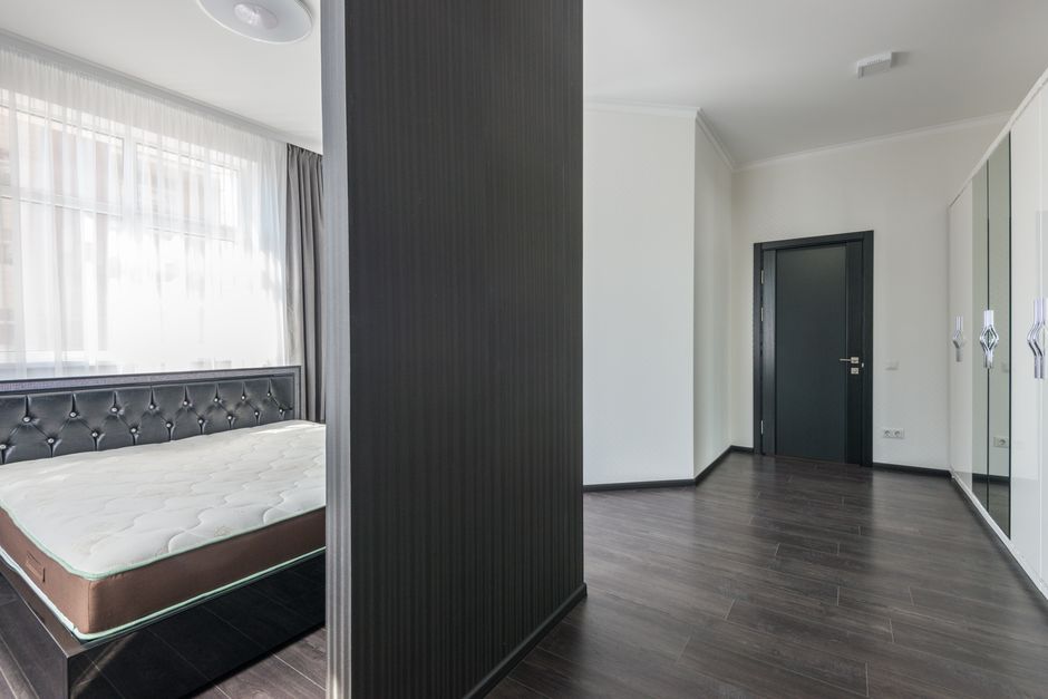 Interior of modern white apartment with comfortable furniture and soft bed with wooden parquet in daylight