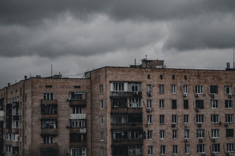 A moody urban scene showcasing a brick apartment building under a gloomy sky, emphasizing architecture and weather.
