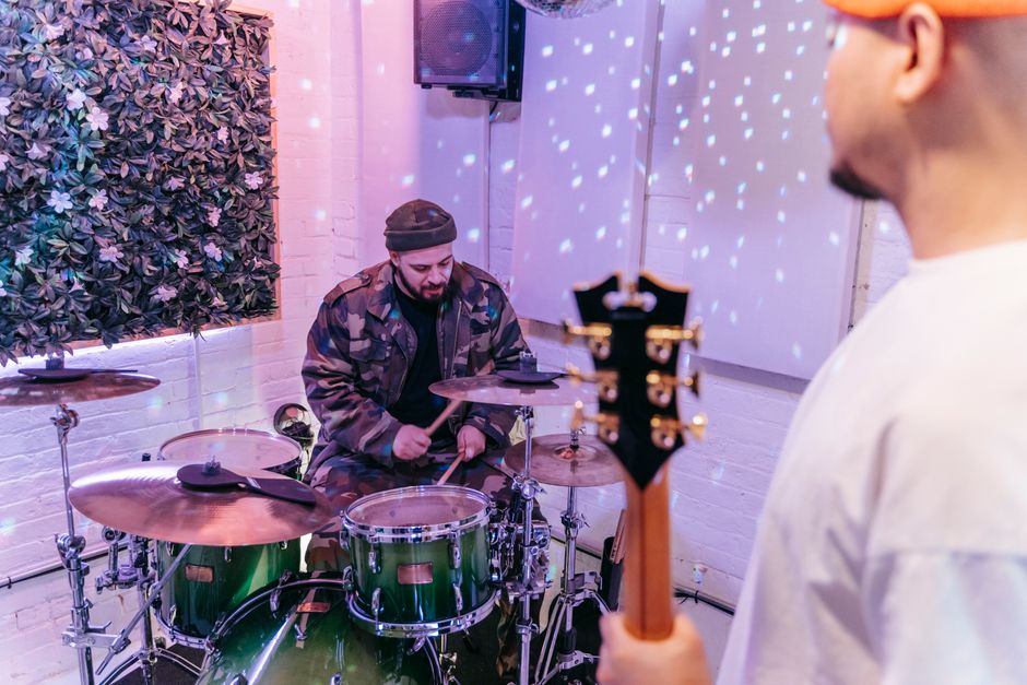 Musicians engaged in a lively jam session with drums and guitar in a studio environment.