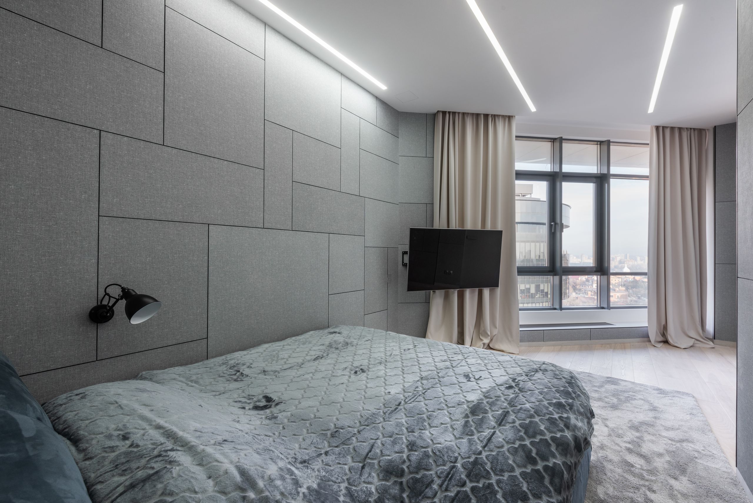 Interior of modern flat with bed on carpet near TV and windows with curtains in daytime
