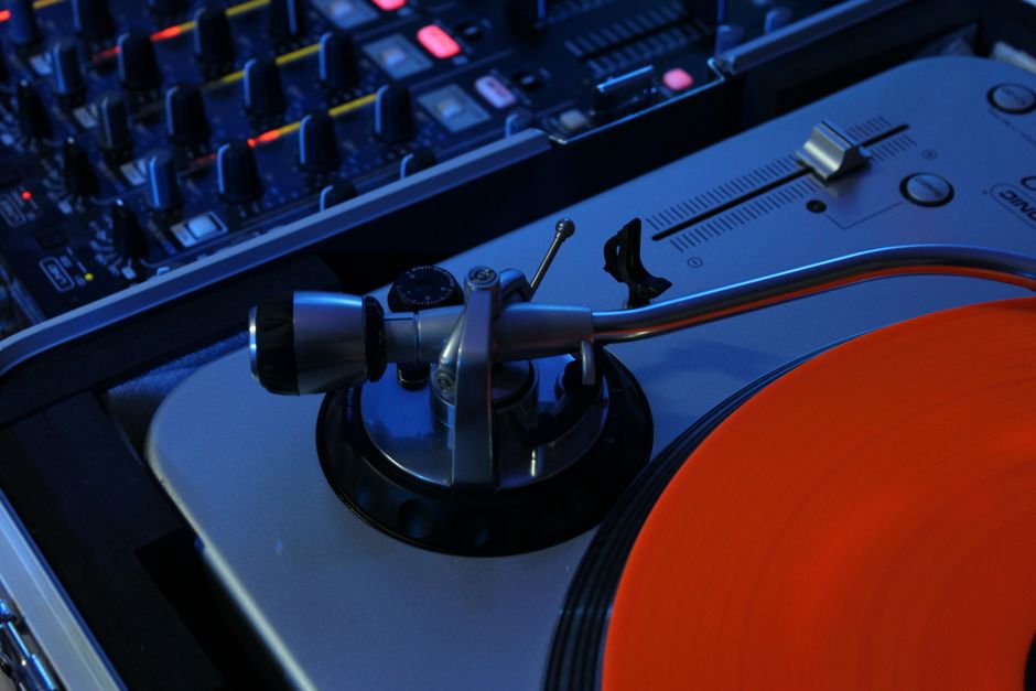 Detailed view of a turntable and audio mixer in a music studio setting, ideal for DJ and sound production concepts.