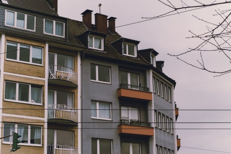 European-style residential building exterior with balconies, under an overcast sky.