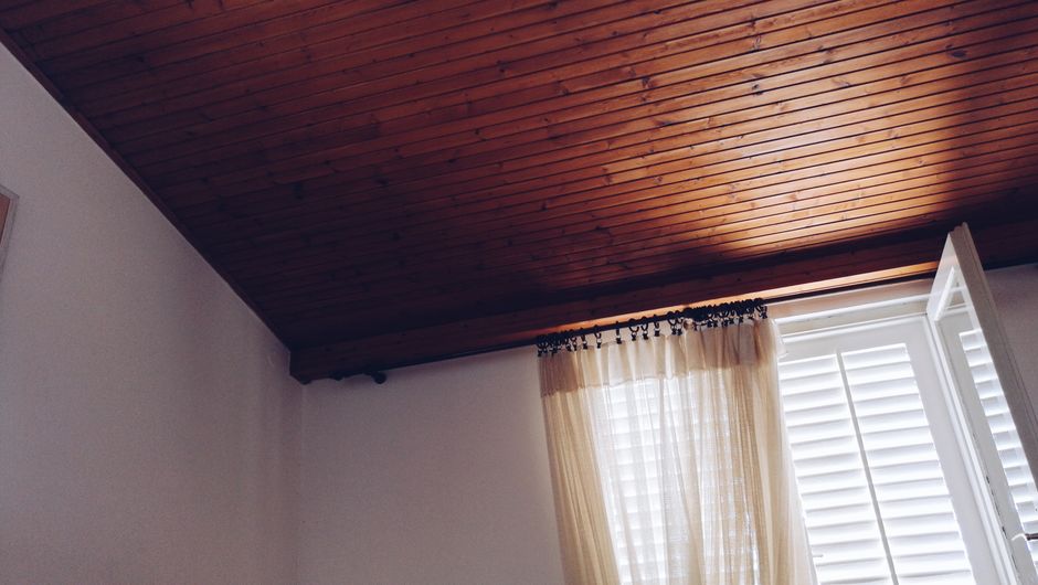 Warm interior with wooden ceiling and sunlit window, offering a cozy and inviting atmosphere.