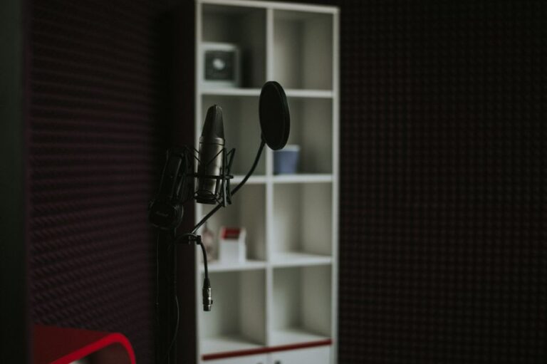 Close-up of a condenser microphone in a soundproof recording studio with modern shelving.